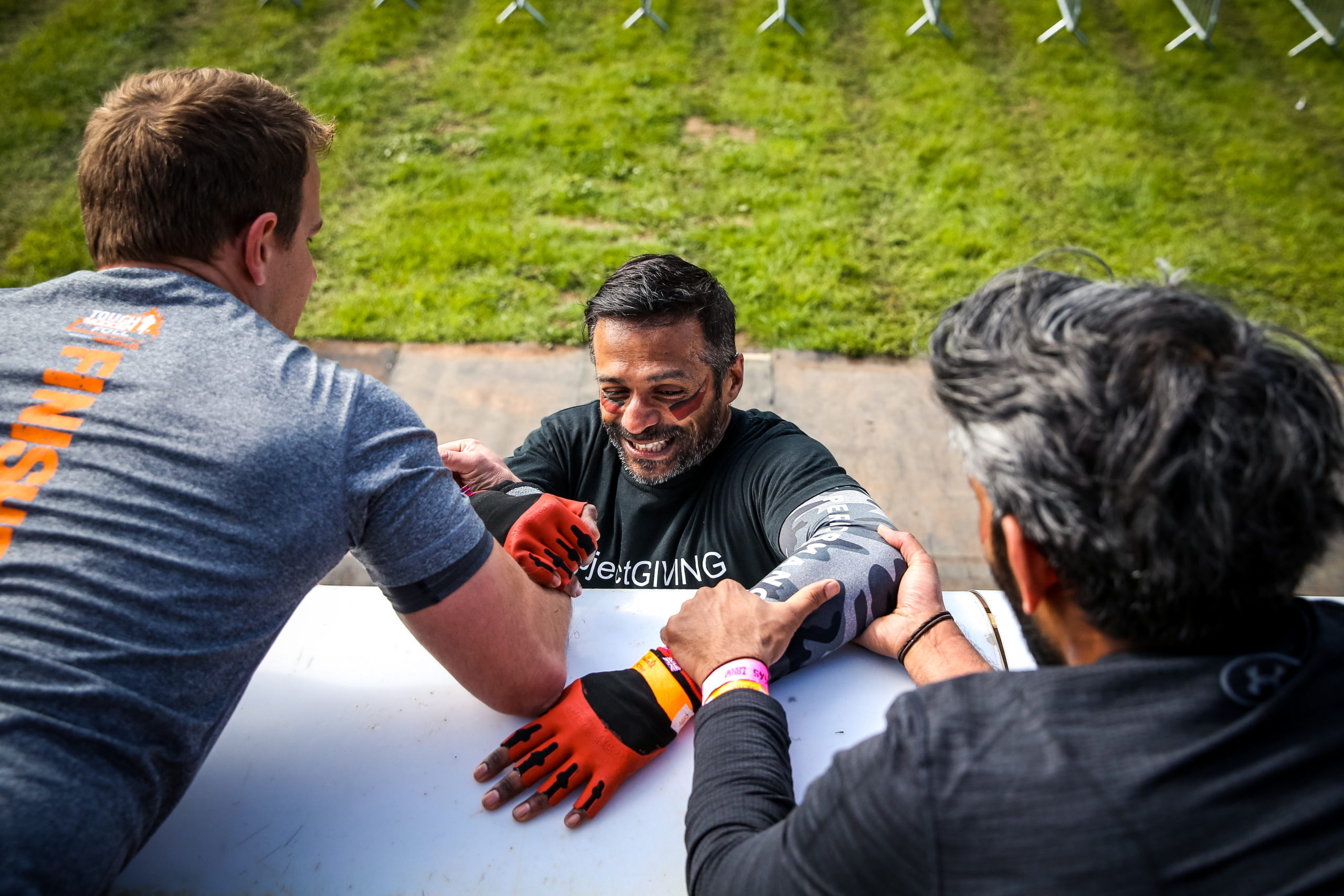 Two people pull a third over the top of a quarter pipe.