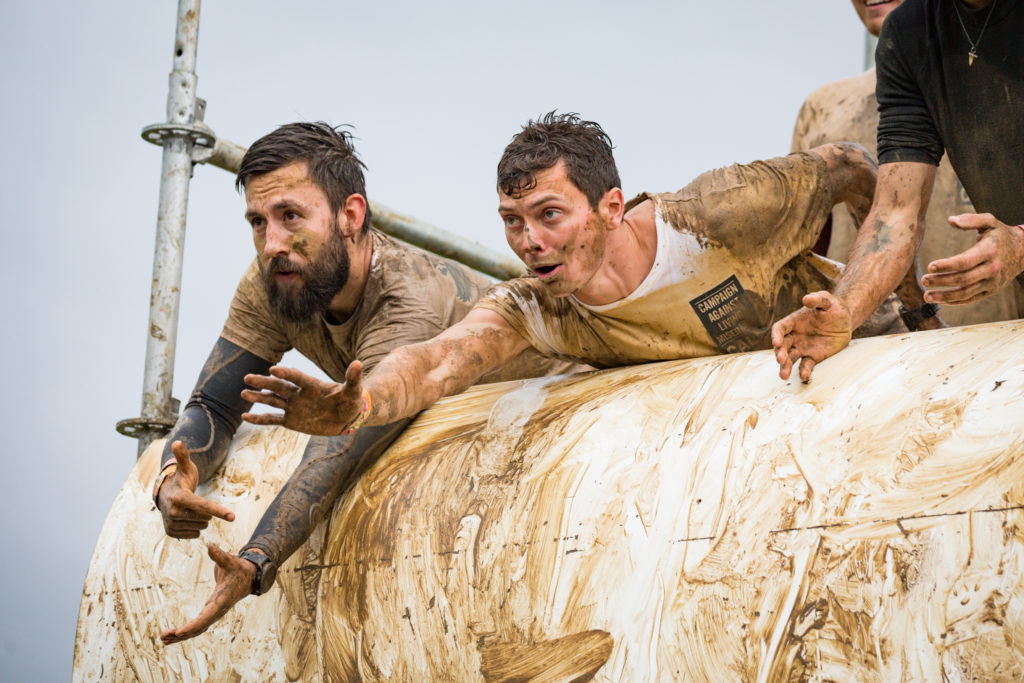 Two men on muddy obstacle