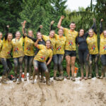 Group participants smiling for a pose with mud in their bodies