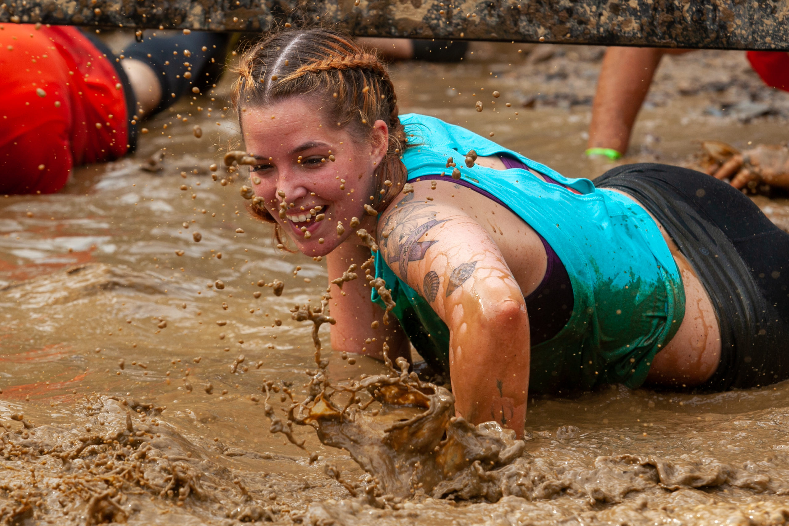Participant smilling while crawling in the mud