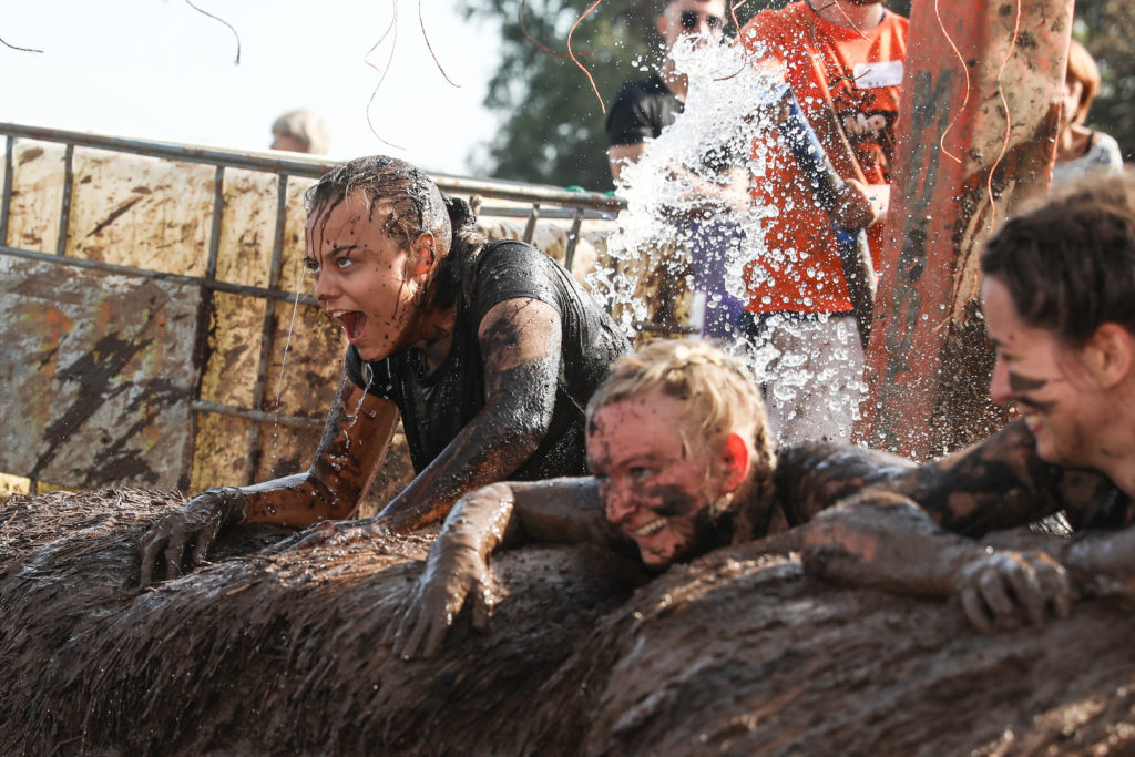 girls laughing in mud water obstacle