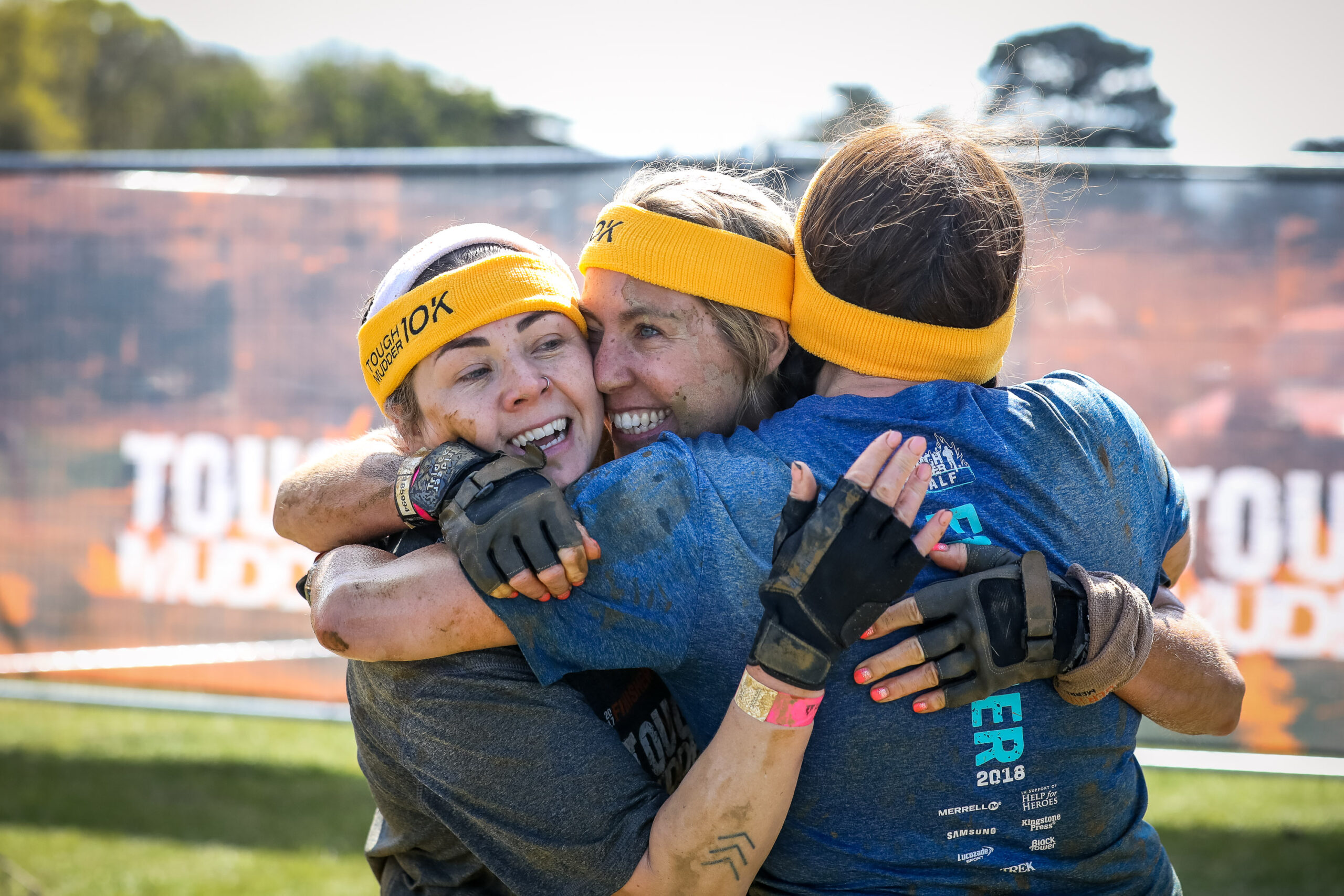 three people hugging at Tough Mudder